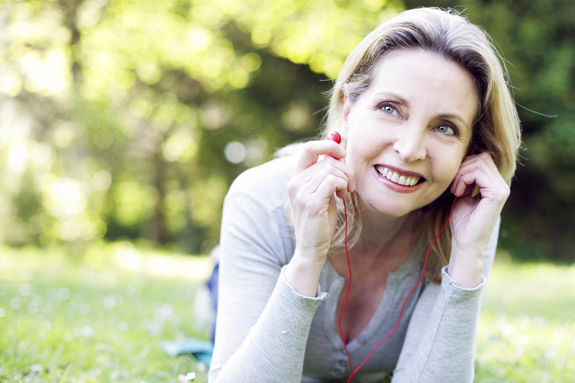 menopause self care – woman at the park listening to music on headphones