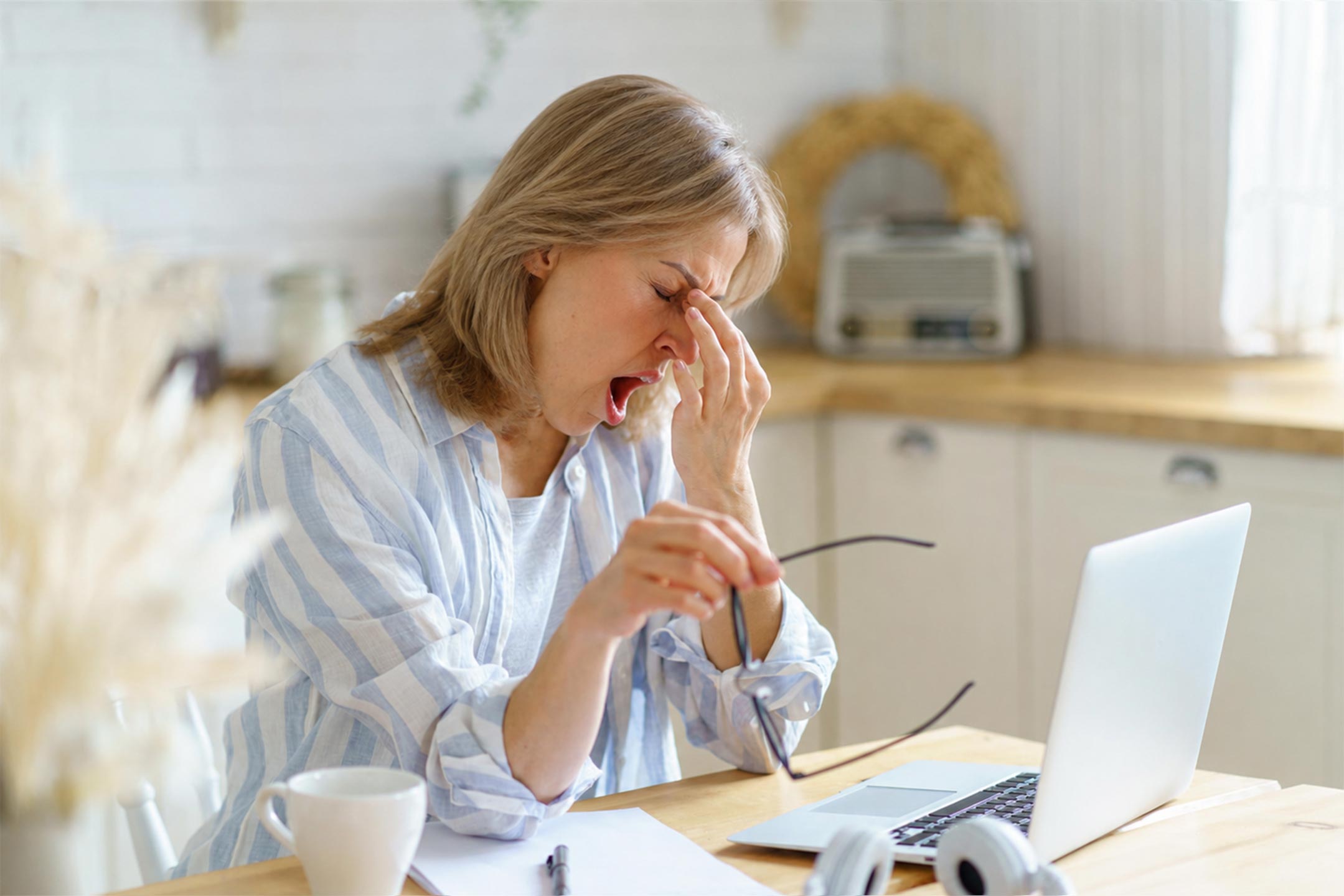 perimenopause fatigue and hormone imbalance - Tired middle-aged woman sitting at kitchen table in the morning